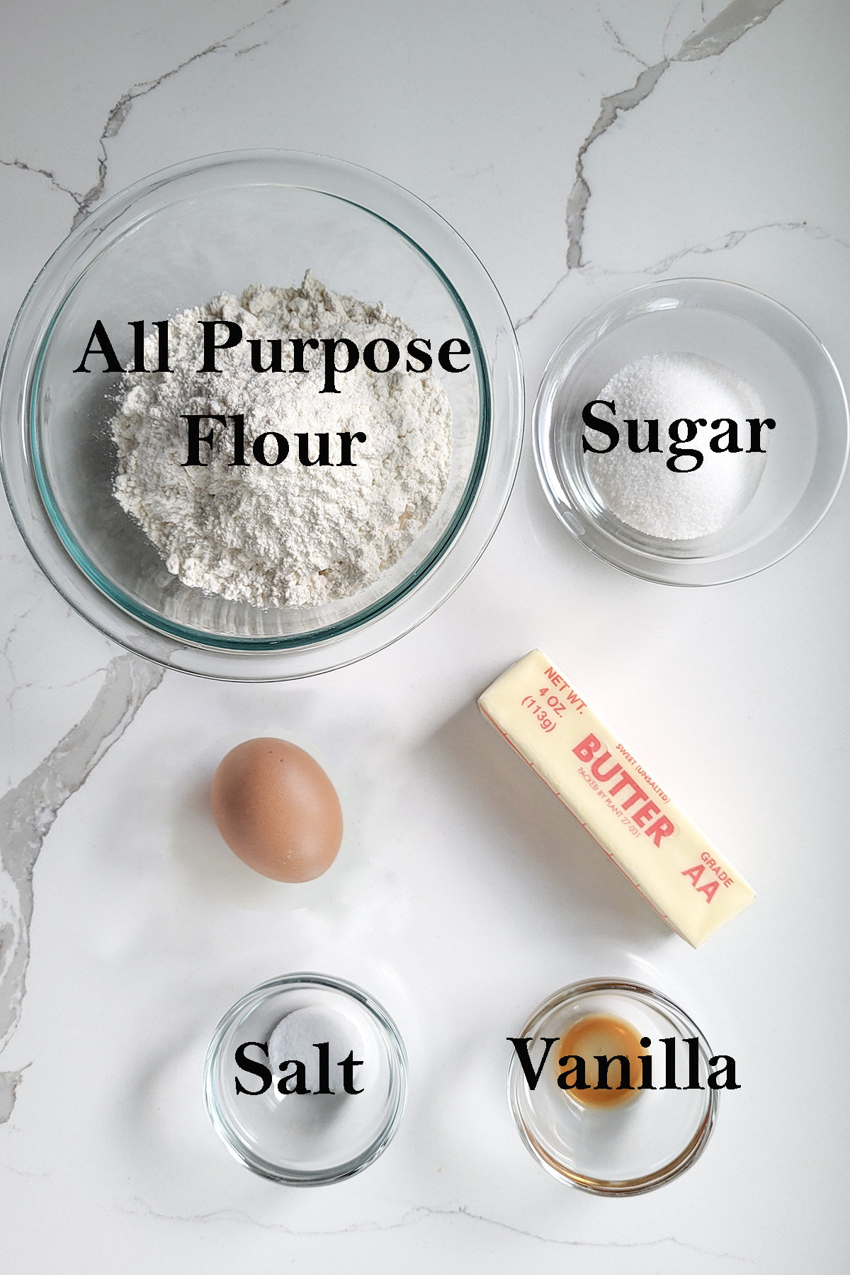 ingredients for short dough in glass bowls on a white surface.