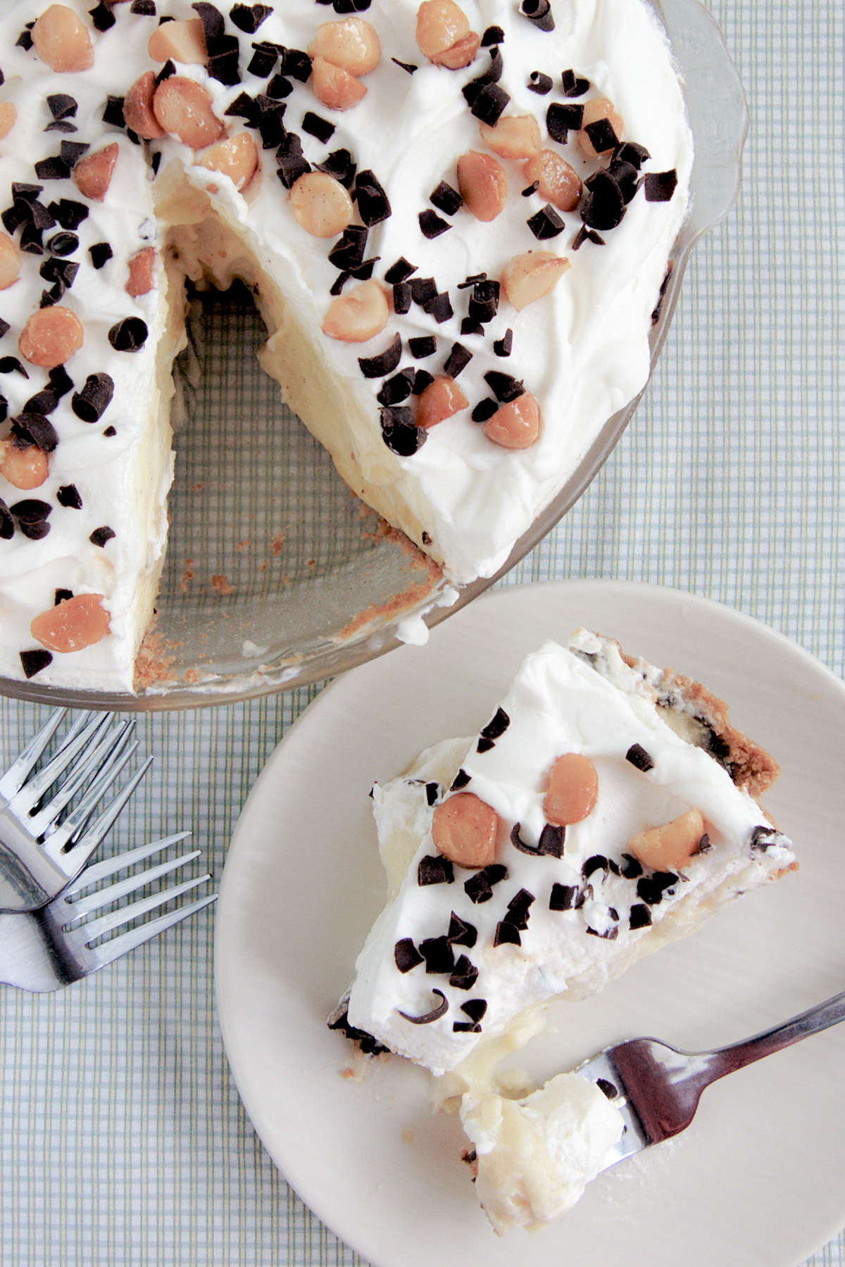 A banana cream pie in a pie pan and a slice of pie on a white plate.