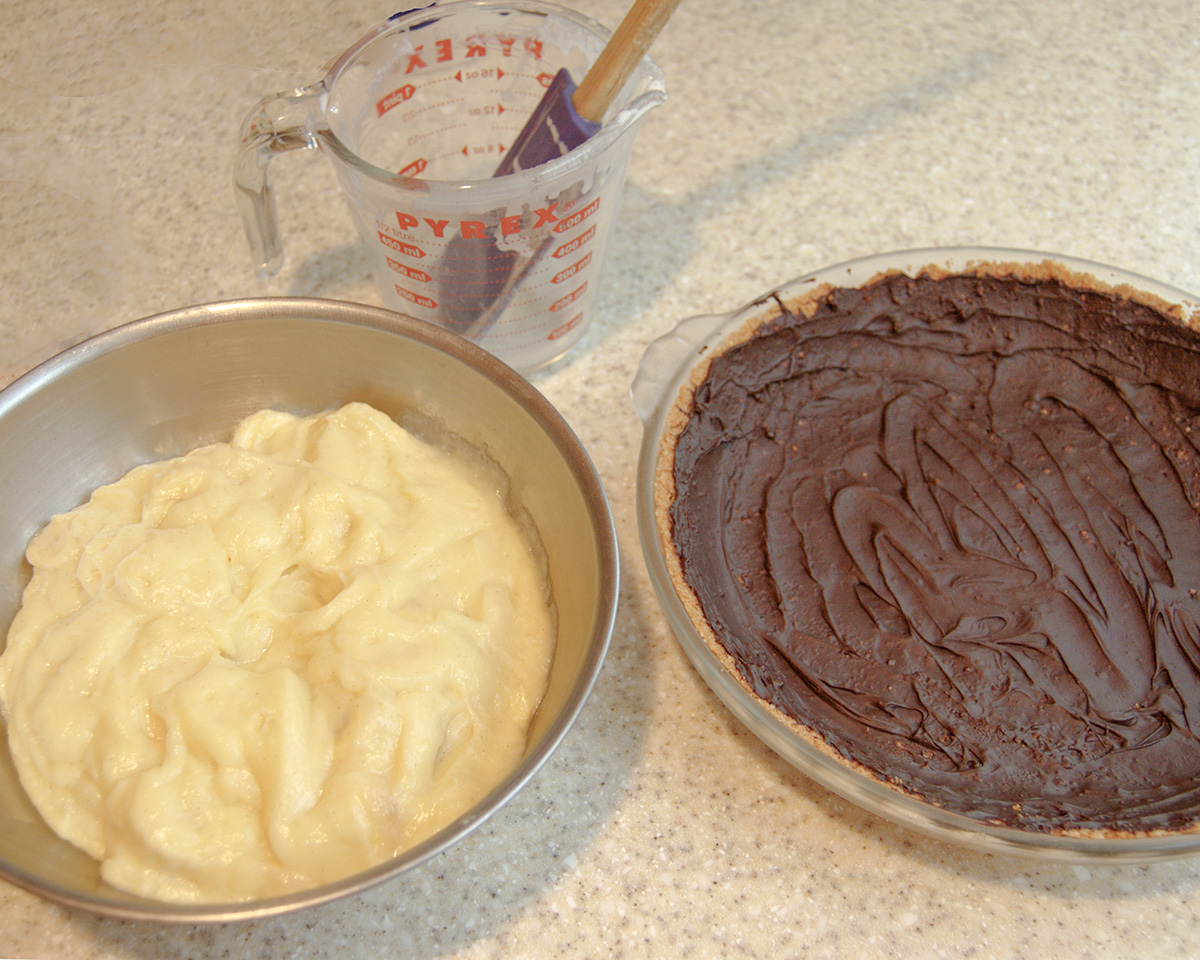 a bowl of banana custard and a chocolate lined pie shell on a marble surface. 