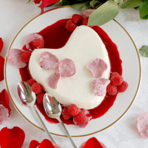 cream heart on a plate with raspberry sauce.