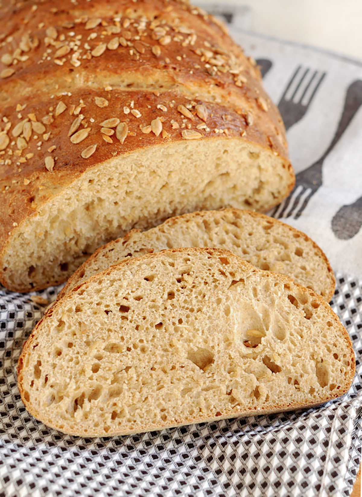 a sliced loaf of cracked wheat bread on a black and white towel.