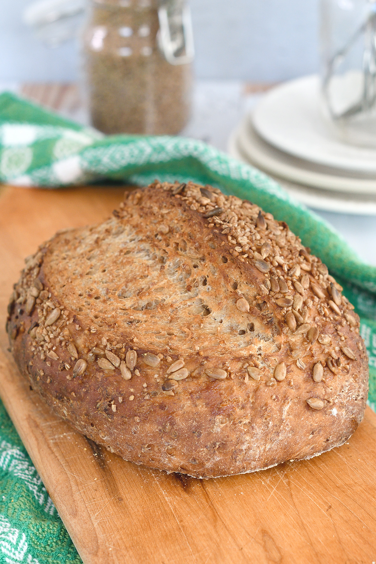 a loaf of cracked wheat bread on a cutting board.