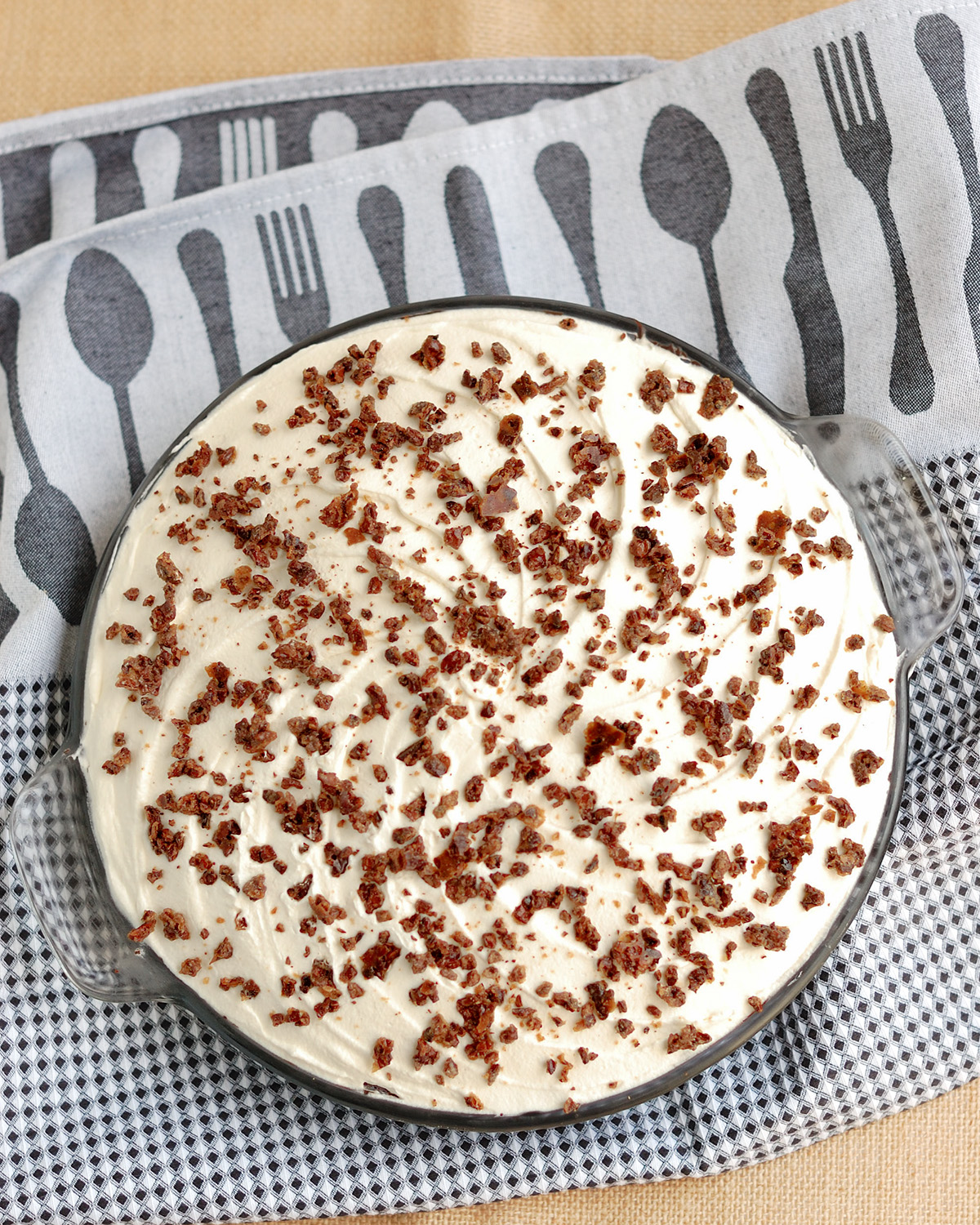 a chocolate cream pie on a white and black tea towel.