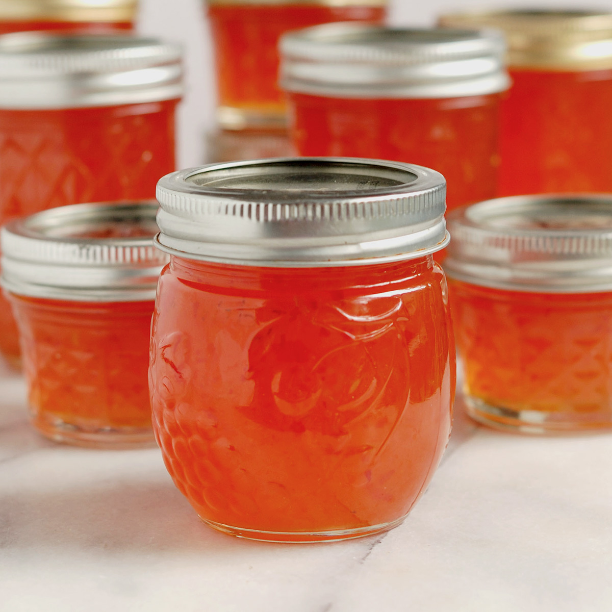 jars of hot pepper jelly on a marble table.