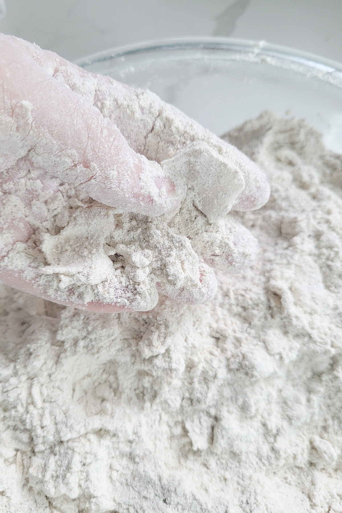 a hand working fat into a bowl of flour.