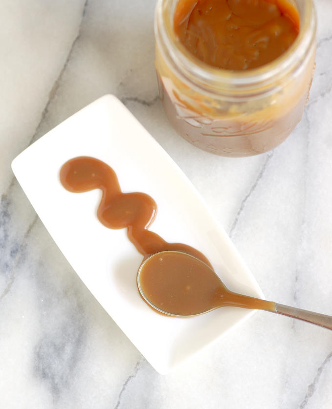 a spoon and a dollop of butterscotch sauce on a white plate.