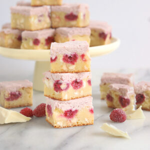 a stack of white chocolate raspberry brownies on a marble table.