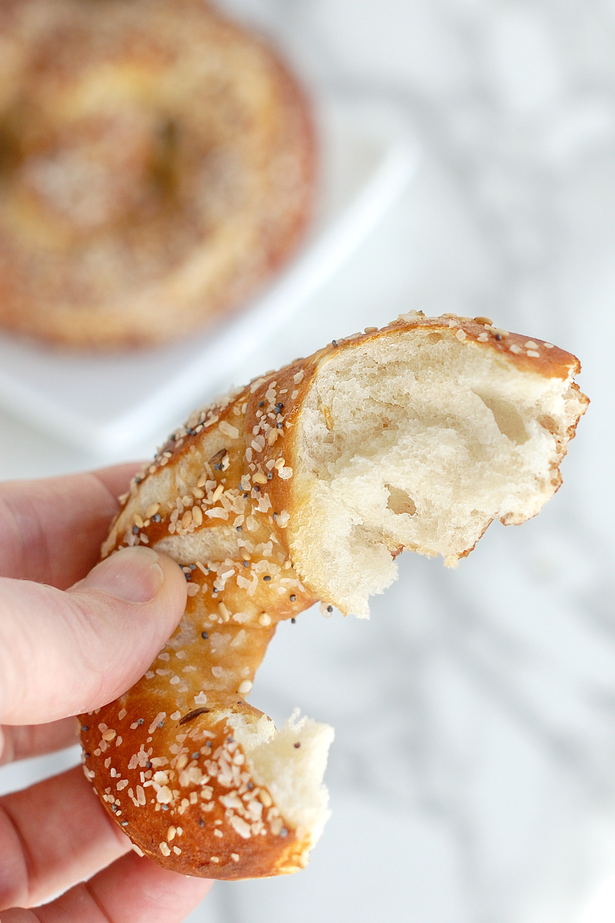 a hand holding a piece of a sourdough soft pretzel.