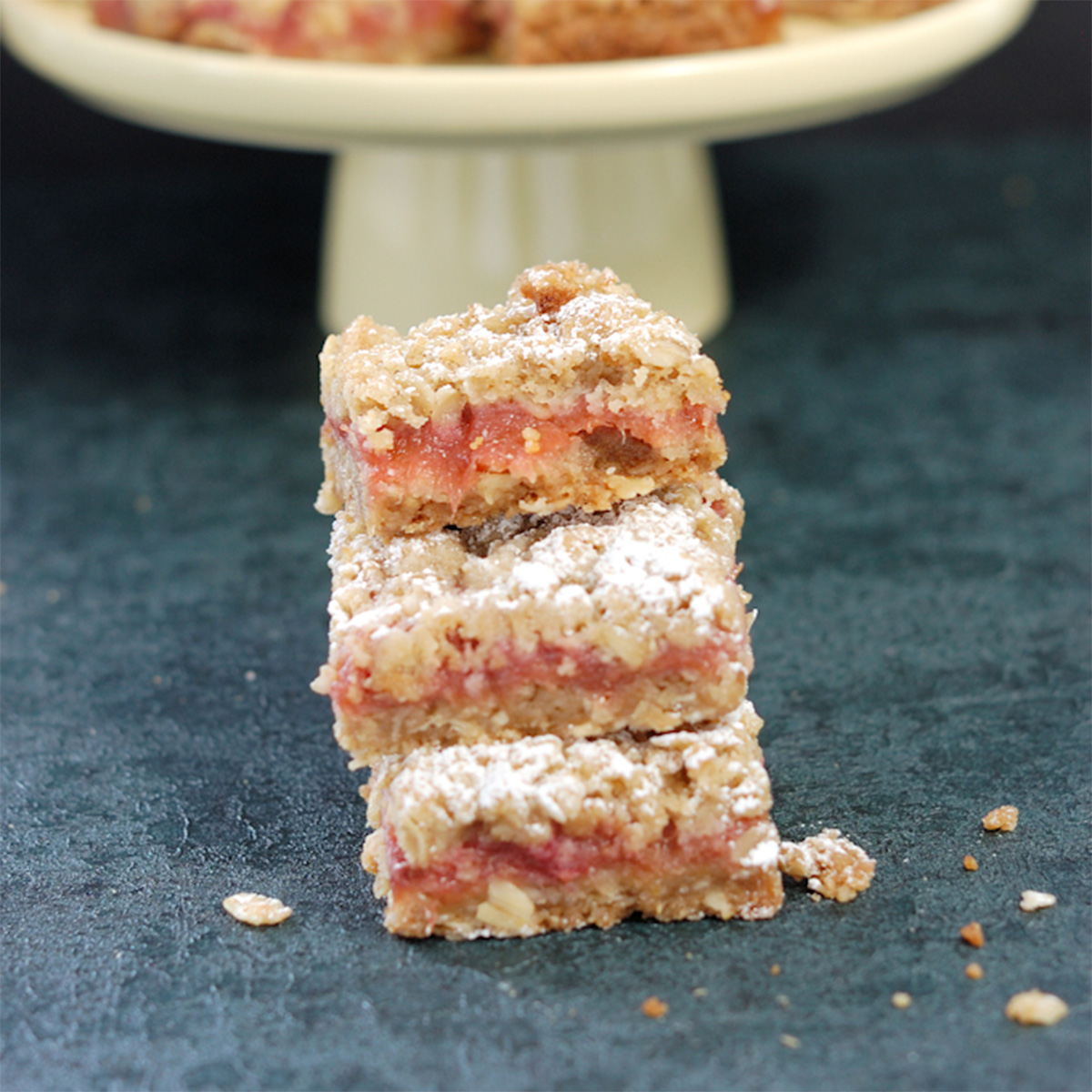 three rhubarb crumble bars on a black surface.