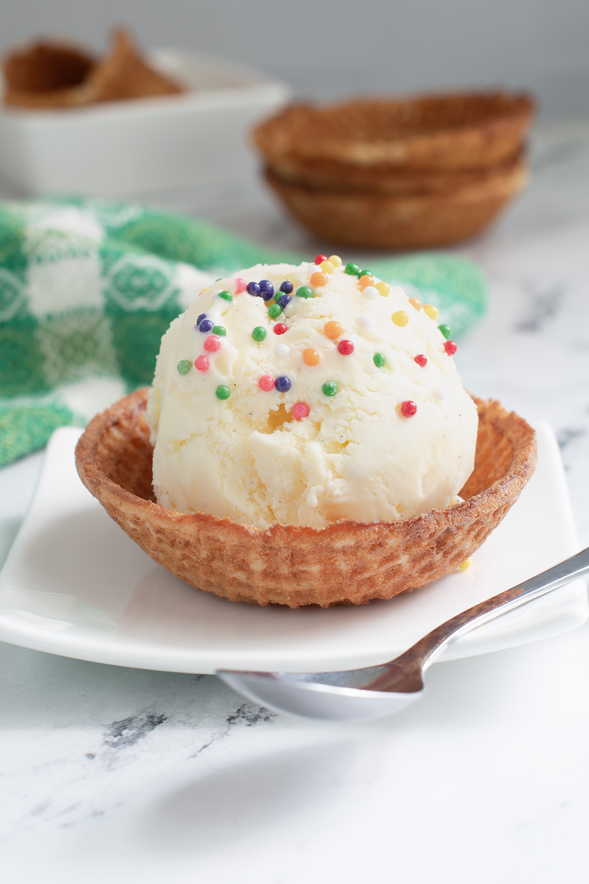 a waffle cone bowl with a scoop of ice cream on a white plate.