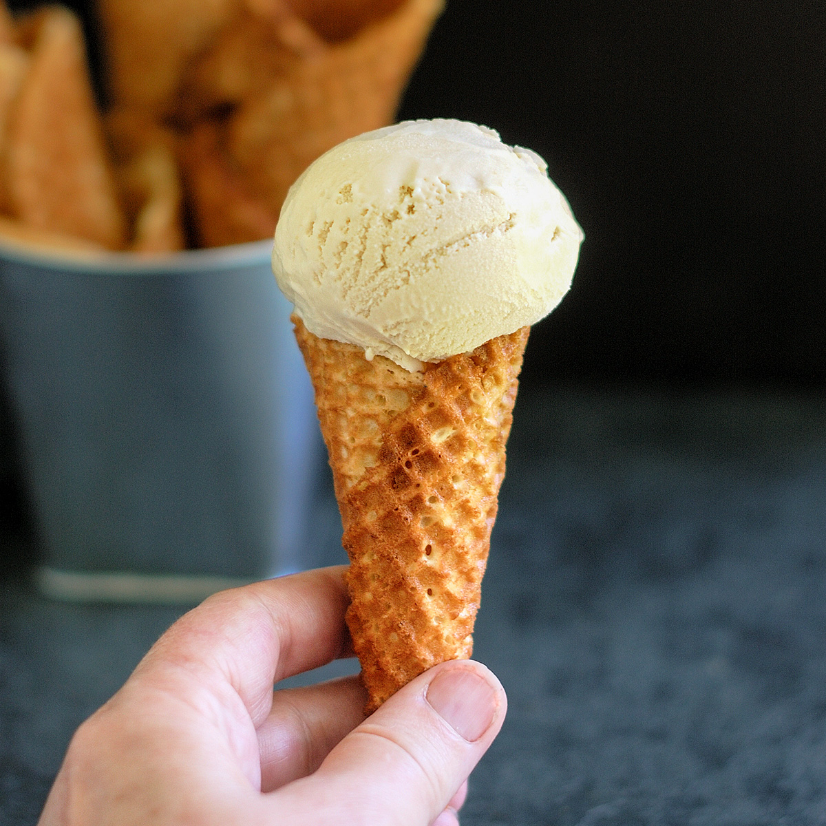 a hand holding an ice cream cone with 1 scoop.