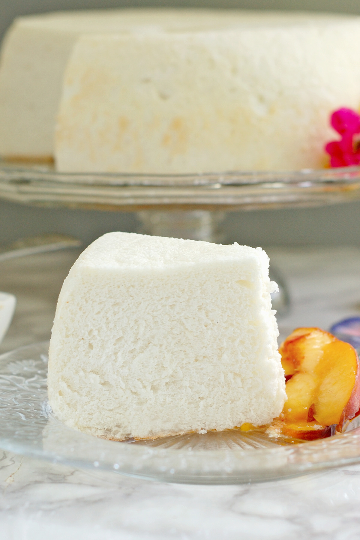 a slice of angel food cake with peaches on a glass plate.