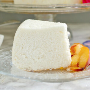 a slice of angel food cake with peaches on a glass plate.