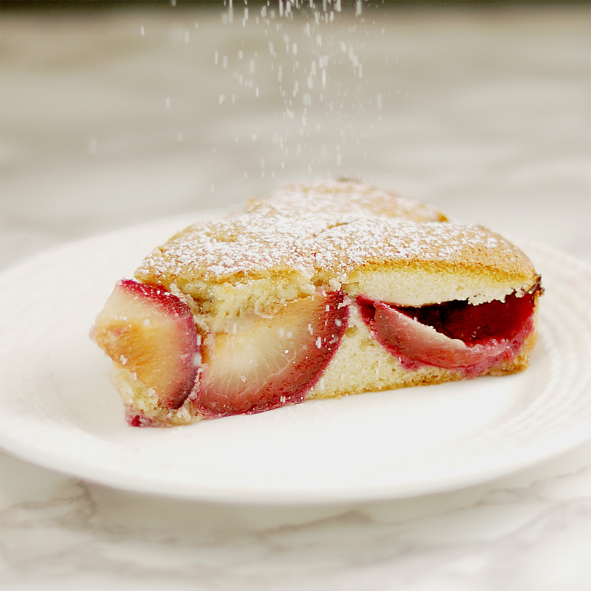 a slice of plum cake on a white plate.