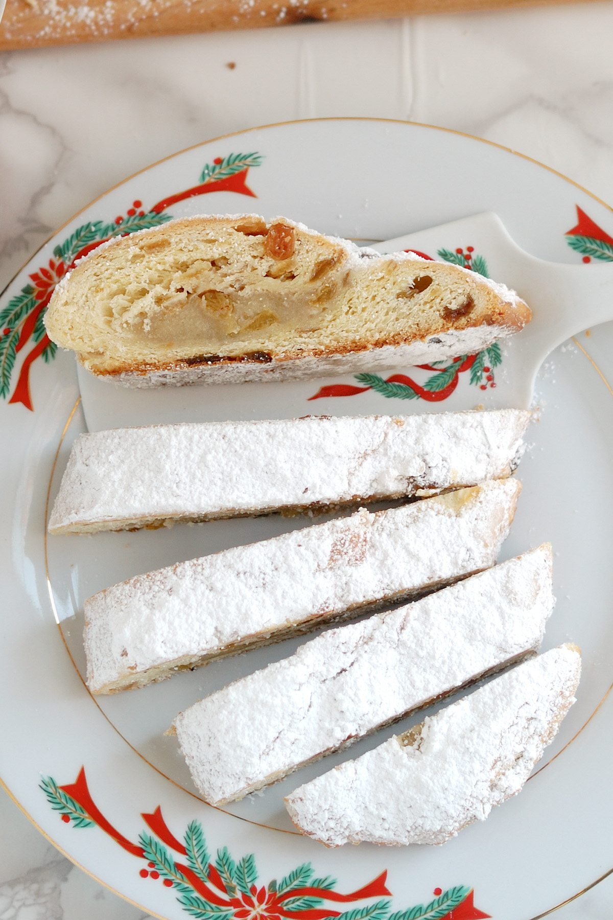 a sliced almond stollen on a Christmas plate. 