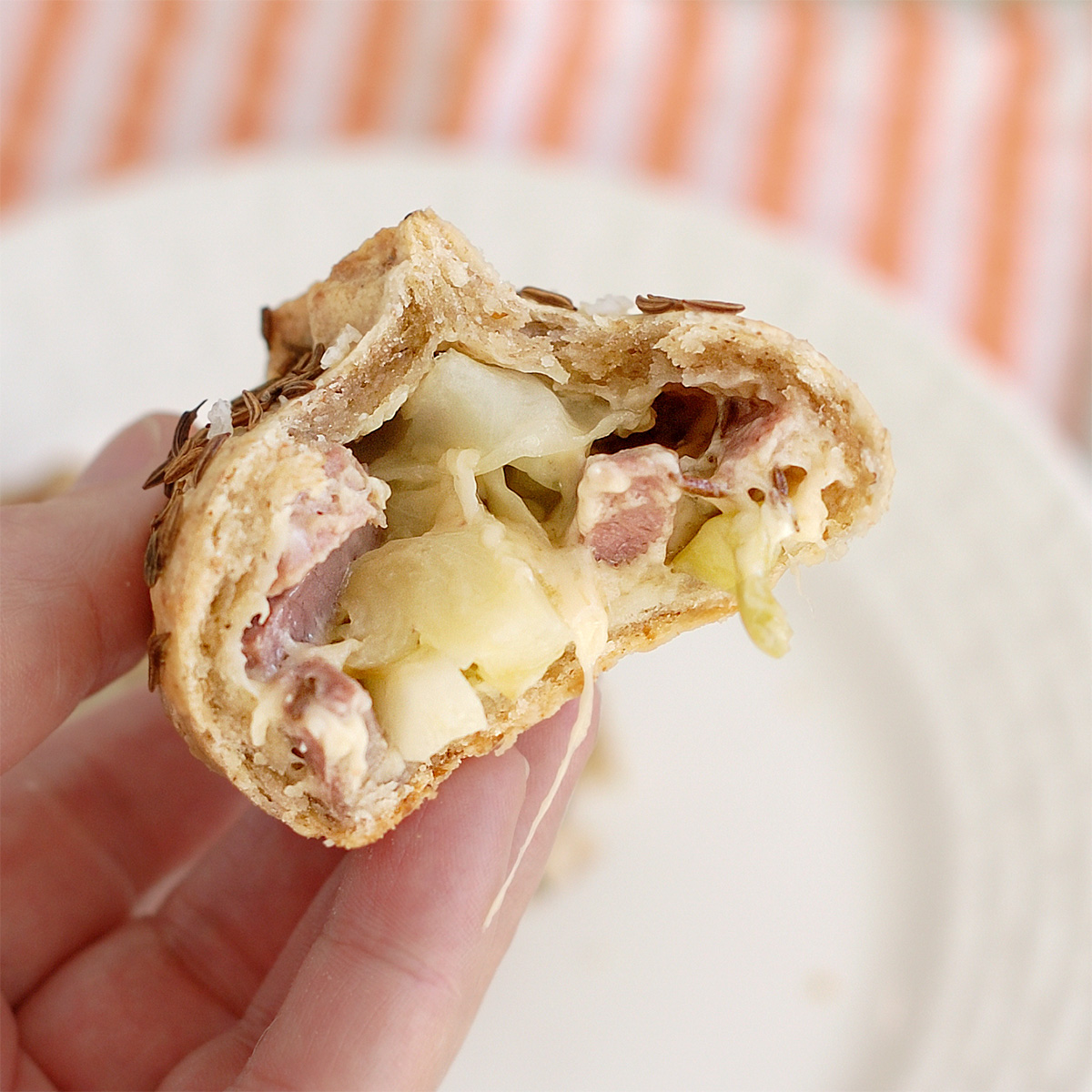 a hand holding half a corned beef and cabbage pasties.