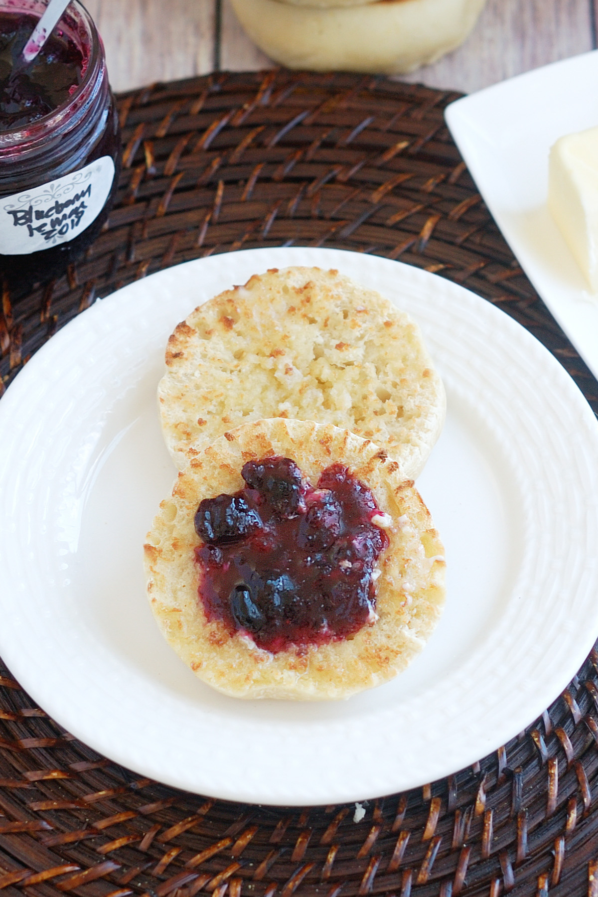 a sourdough english muffin topped with jam on a white plate.