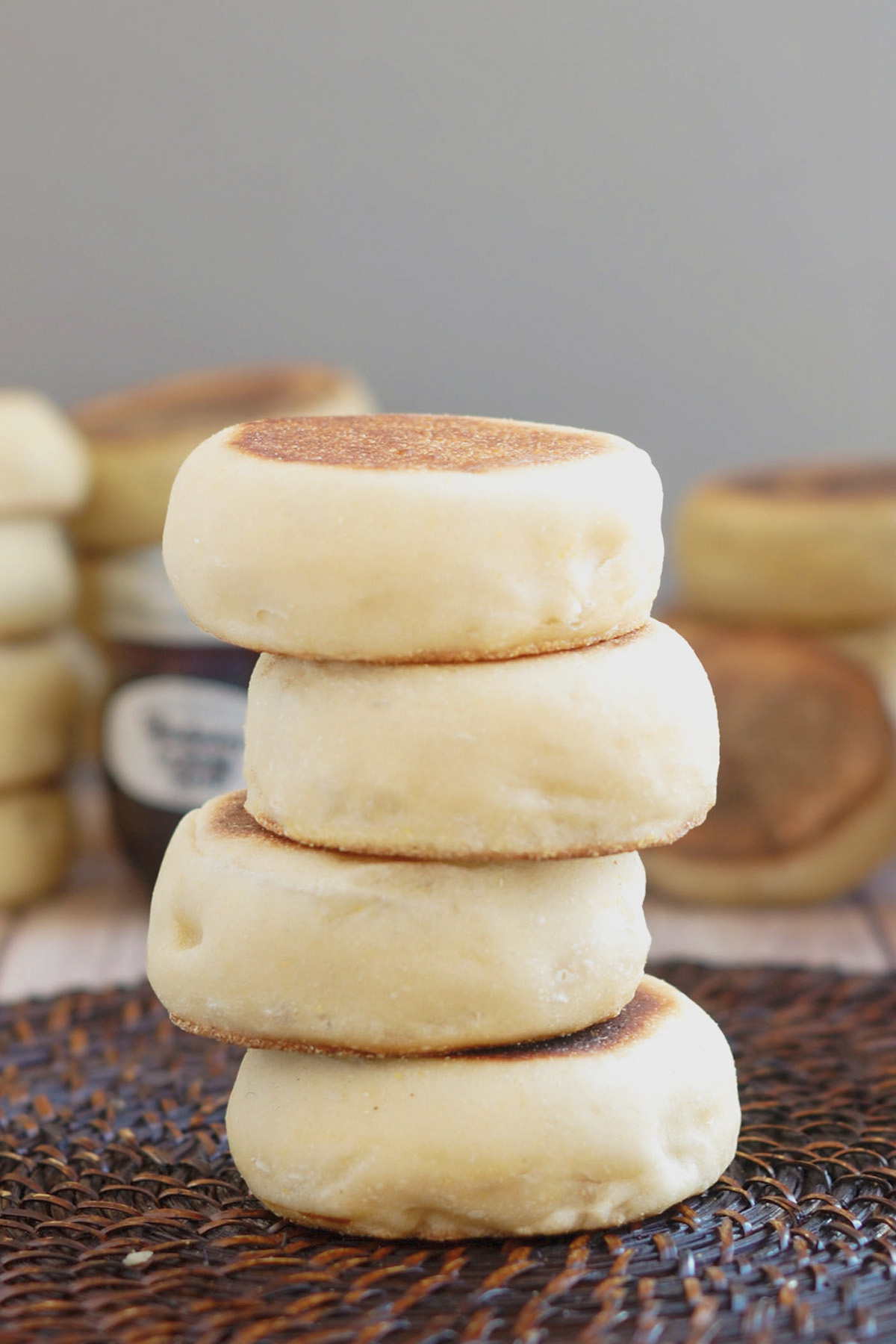 a stack of sourdough english muffins on a brown surface.