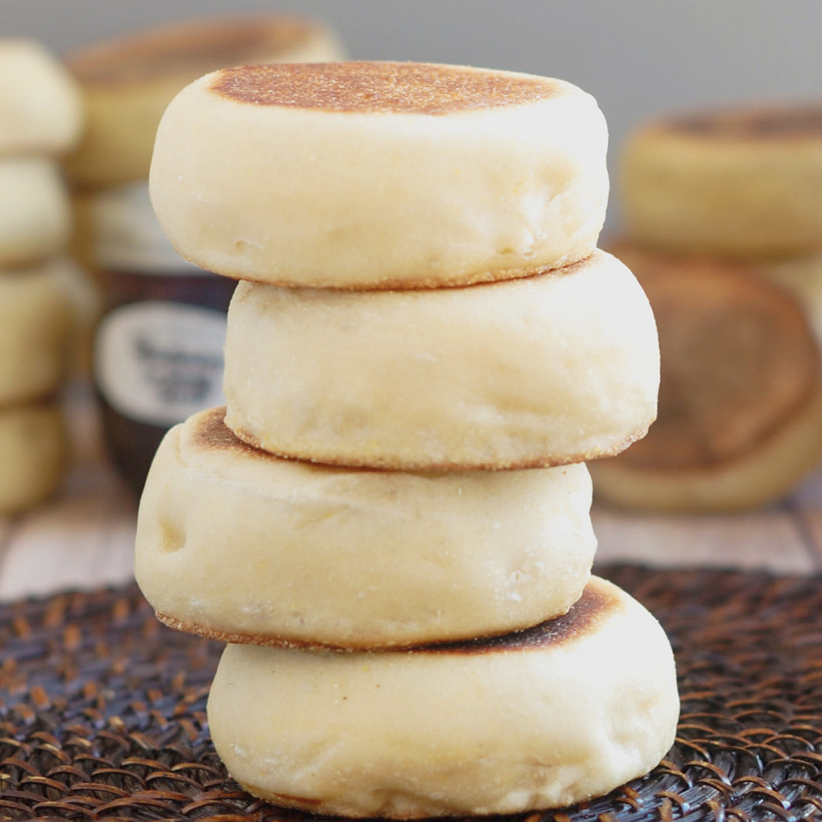 a stack of sourdough english muffins on a brown surface.