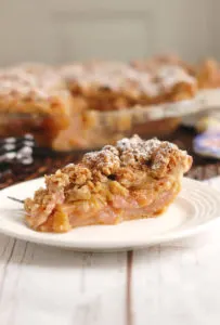 a slice of rhubarb crumb pie on a white plate