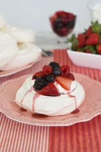 a pavlova with berries and cream on a pink plate