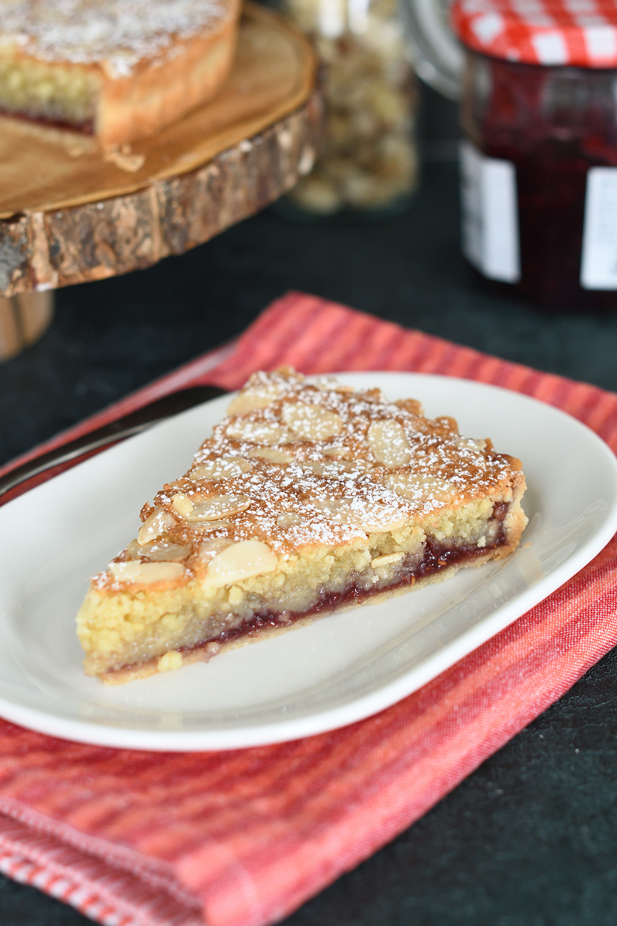 A slice of bakewell tart on a white plate.