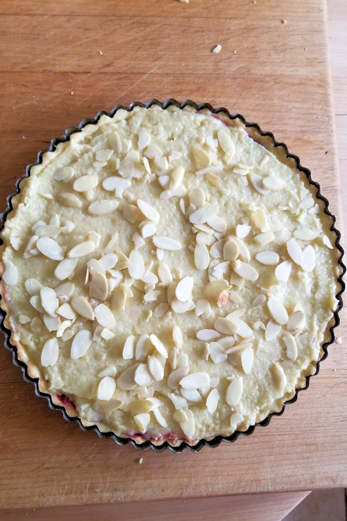 an unbaked bakewell tart on a wooden table.