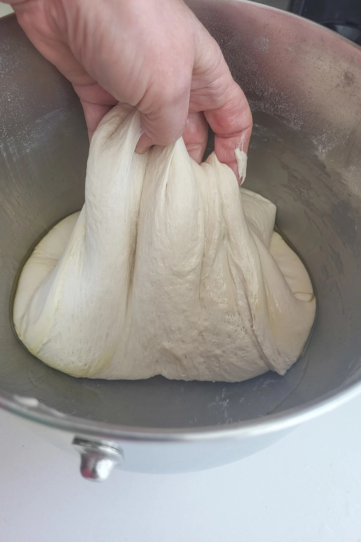 a hand folding dough in a bowl.