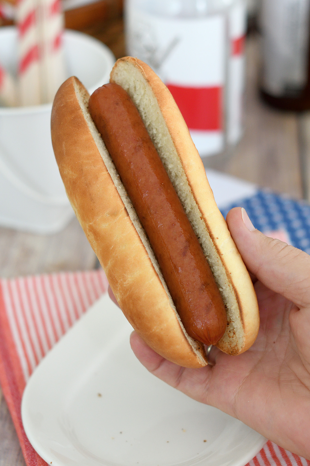 a hand holding a hot dog in a bun.