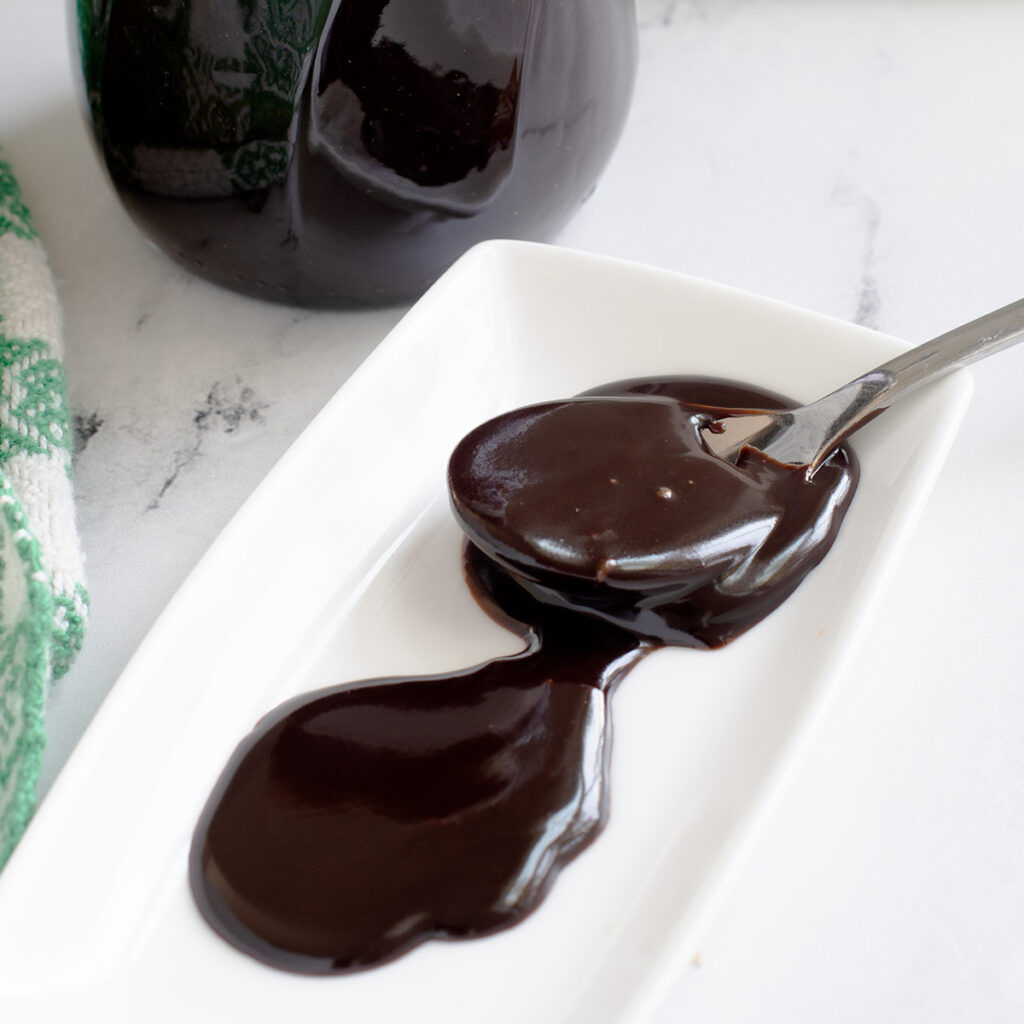 a dollop of hot fudge sauce on a plate with a spoon.