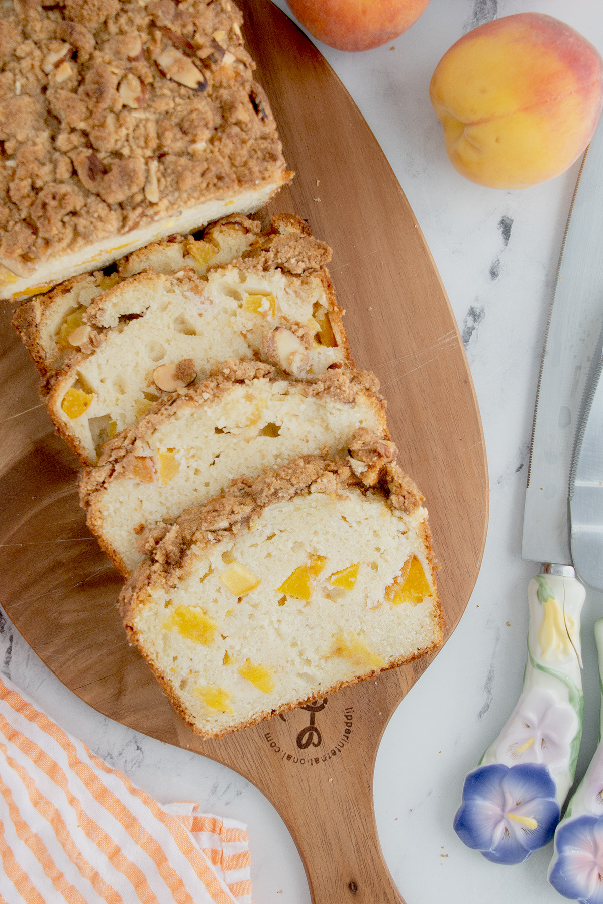 a sliced loaf of peach bread on a wood cutting board.