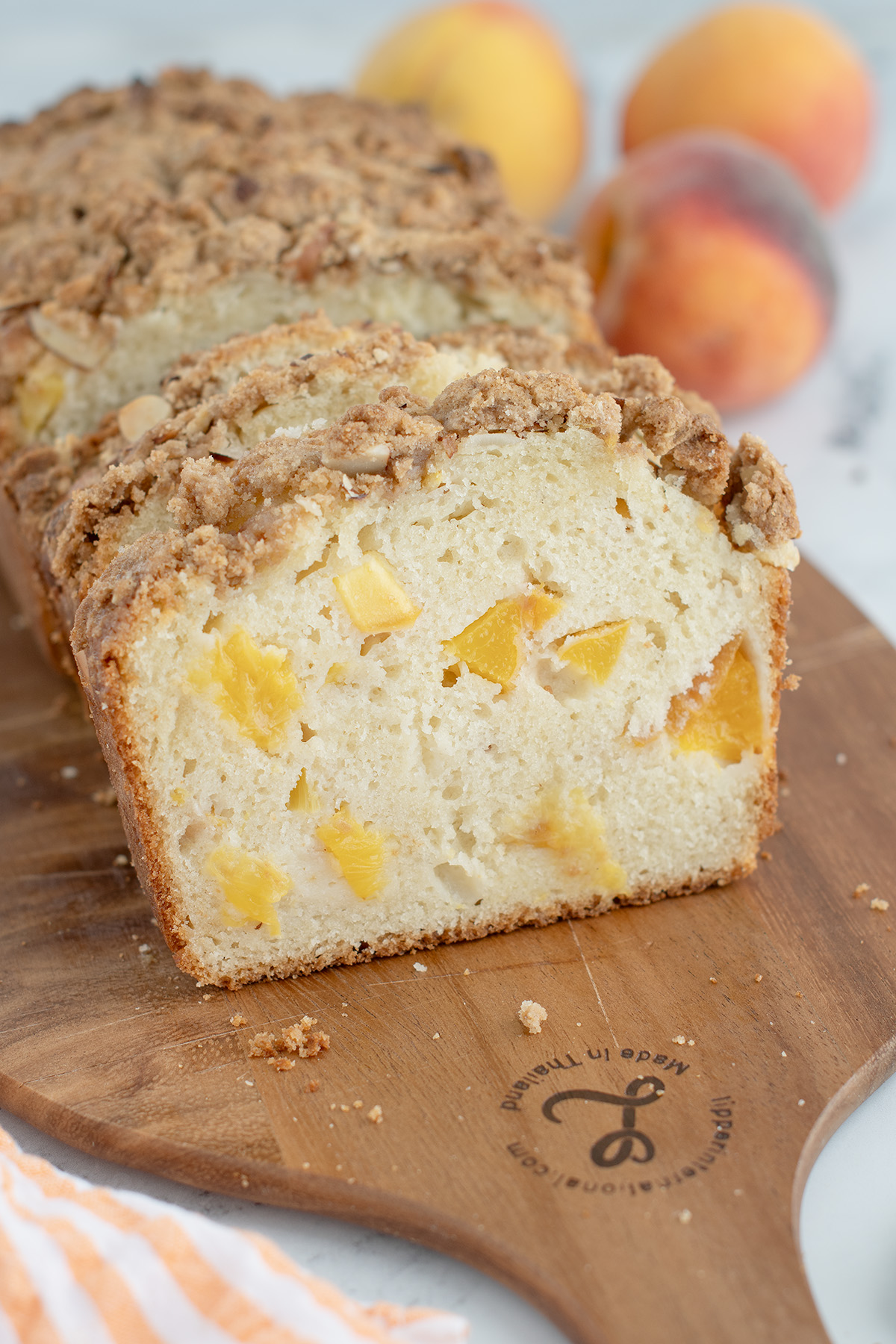 a sliced loaf of peach bread on a wooden cutting board.