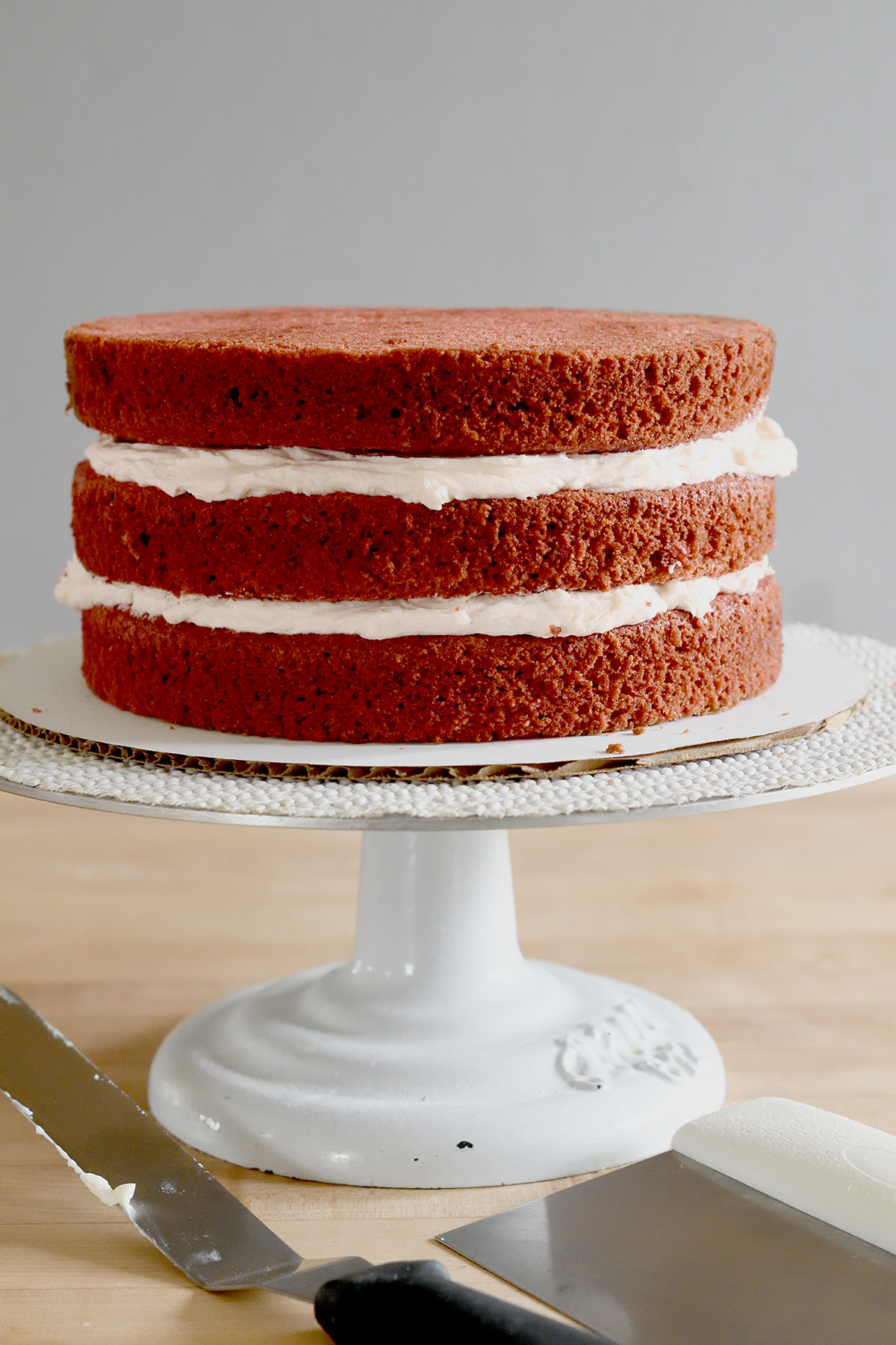 a 3-layer red velvet cake on a cake stand.