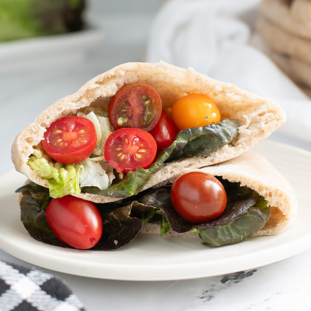 a pita bread filled with lettuce and tomatoes on a white plate.