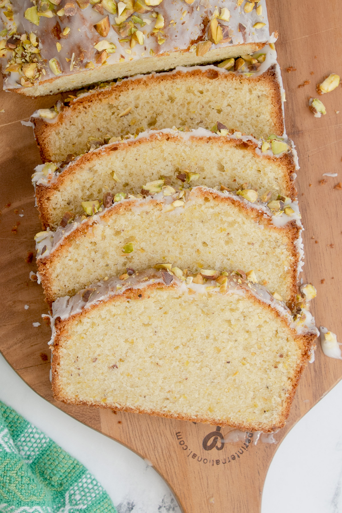 a sliced pistachio pound cake on a wooden cutting board.