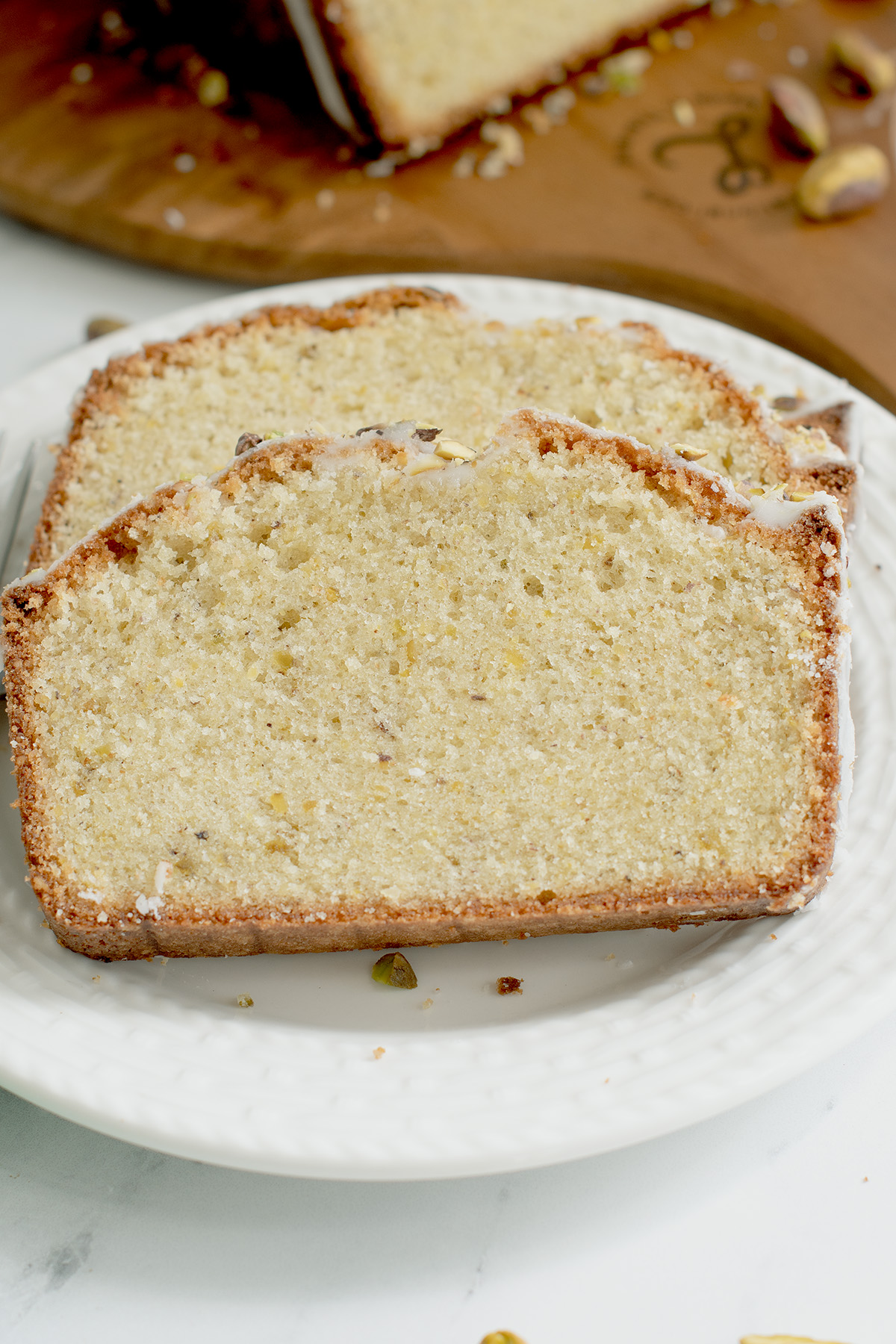 two slices of pistachio pound cake on a white plate.