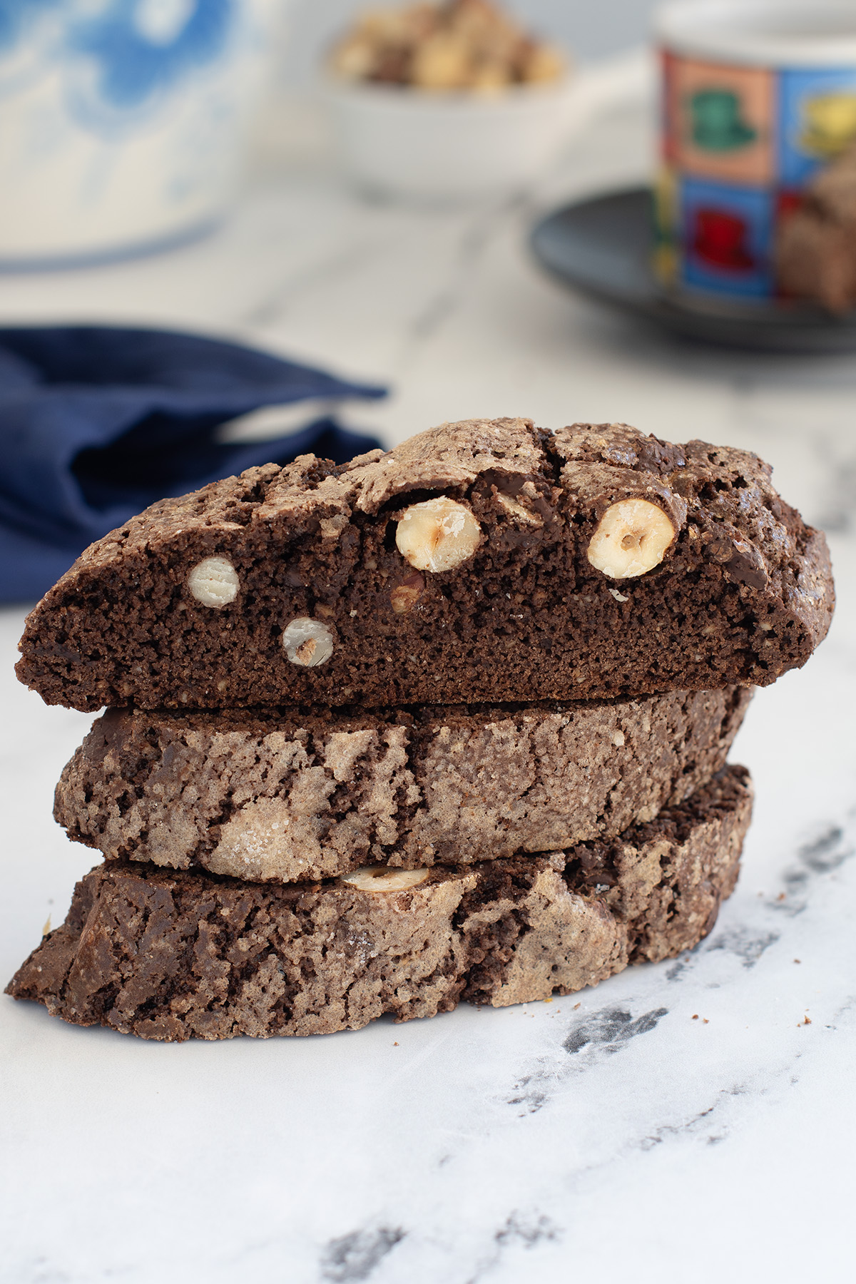 a stack of chocolate and hazelnut biscotti on a marble surface.