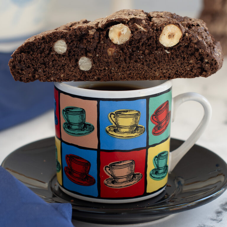 a cup of coffee with a biscotti on top.