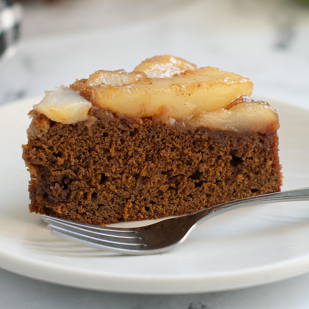 a slice of pear gingerbread cake on a white plate.