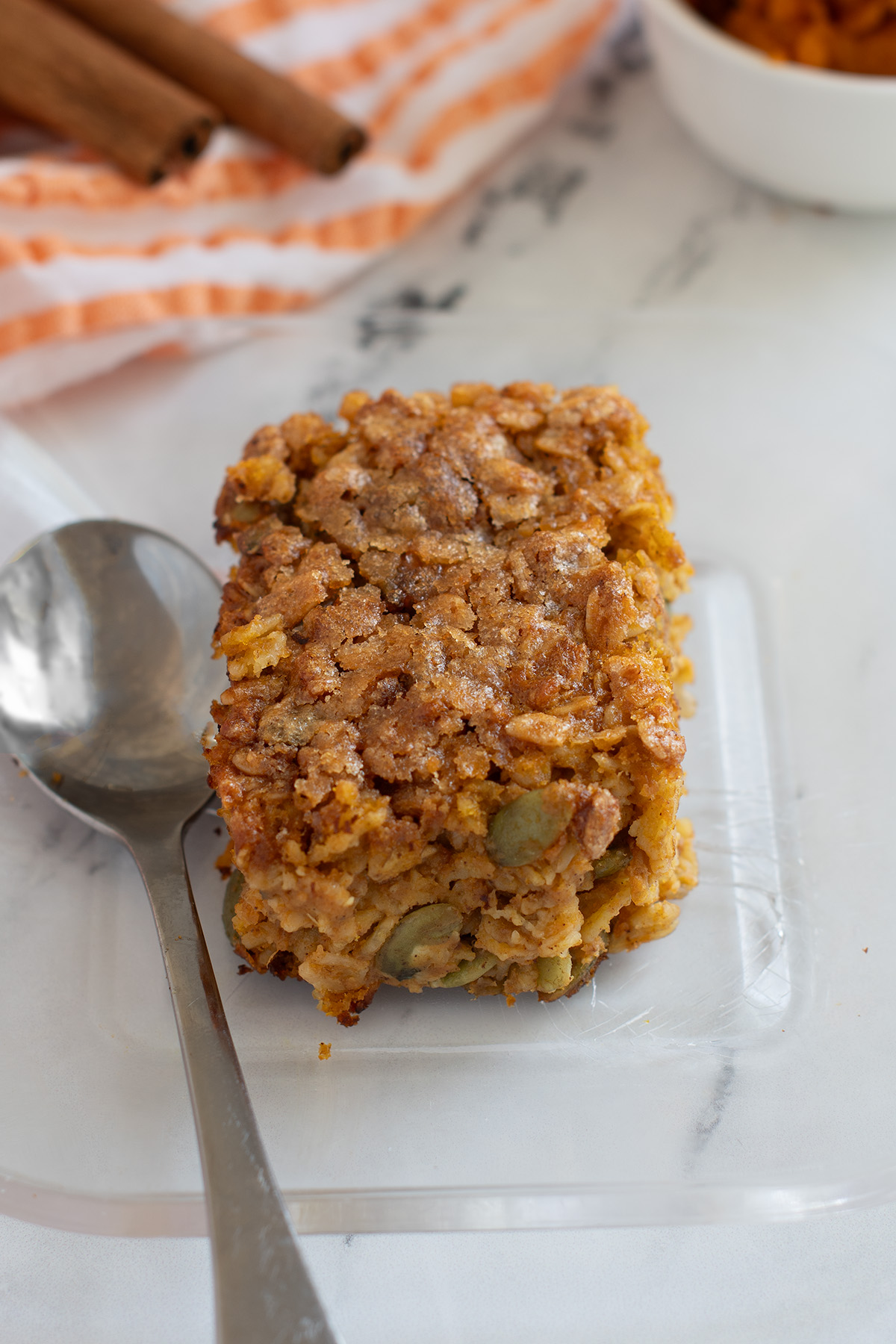 a slice of pumpkin baked oatmeal on a glass plate with a spoon.