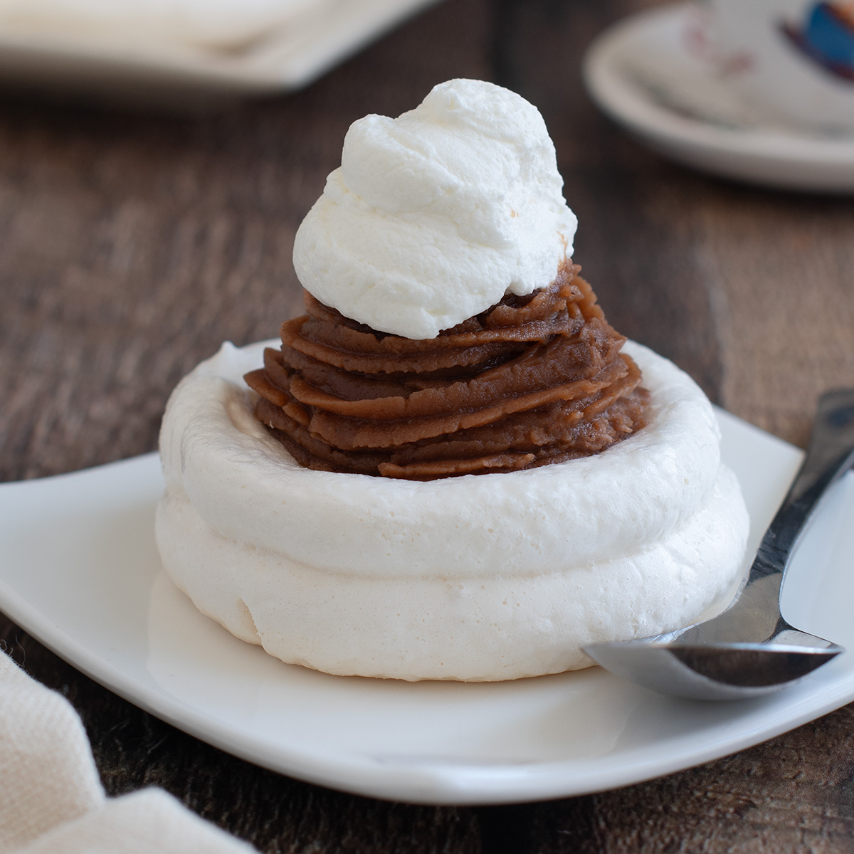 a mont blanc pastry on a white plate with a spoon.