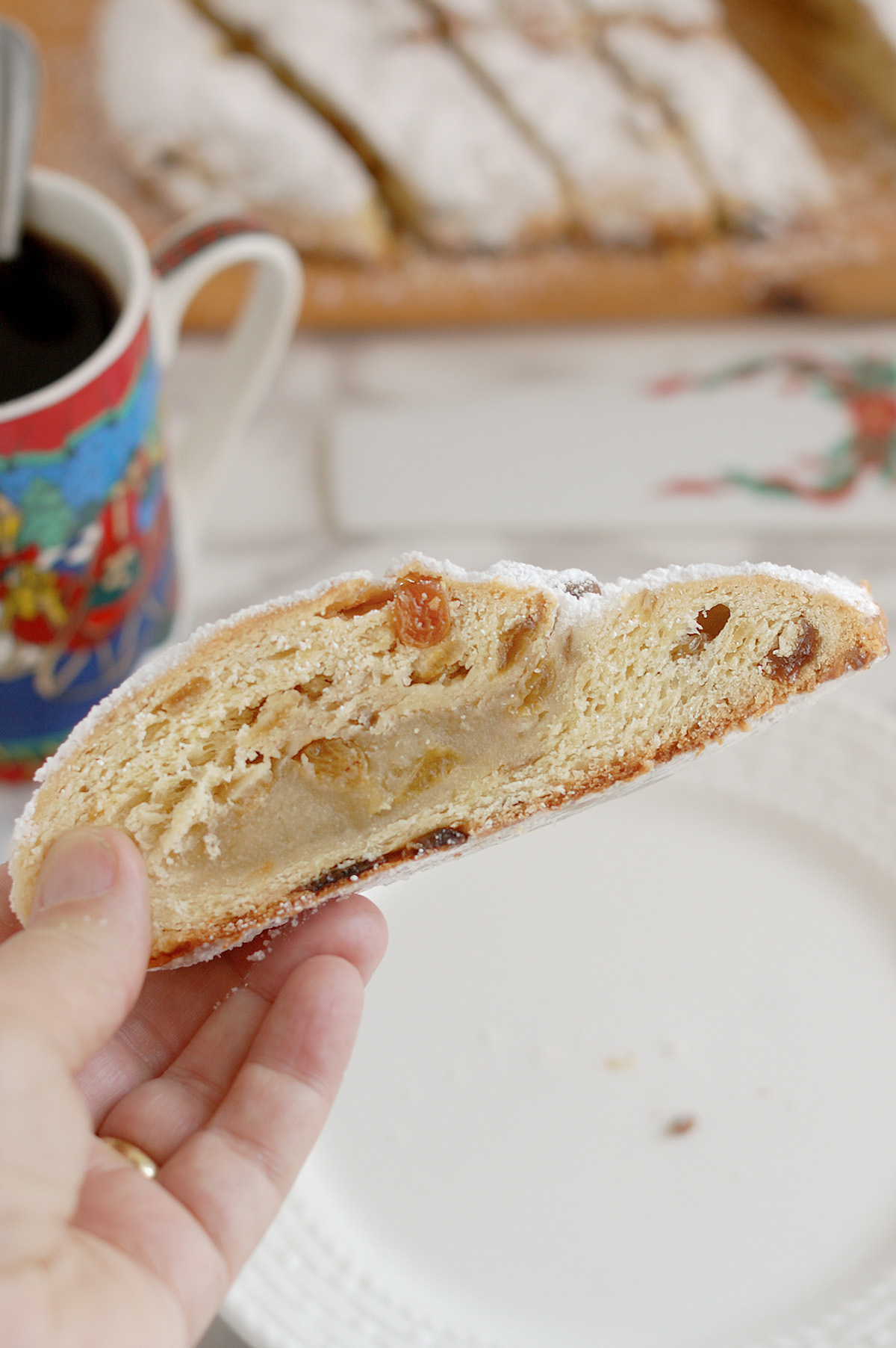 a hand holding a slice of sourdough stollen.