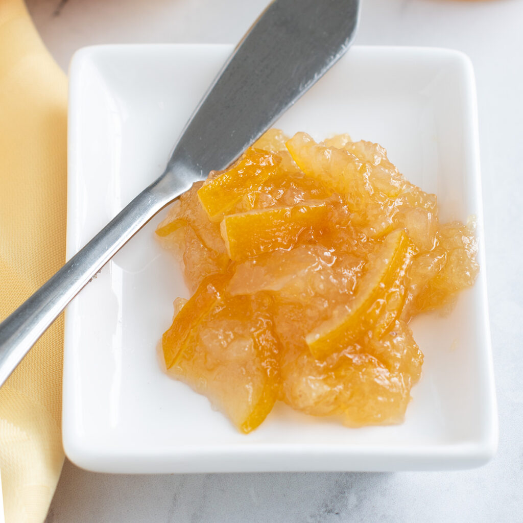 lemon marmalade on a white plate with a butter knife.