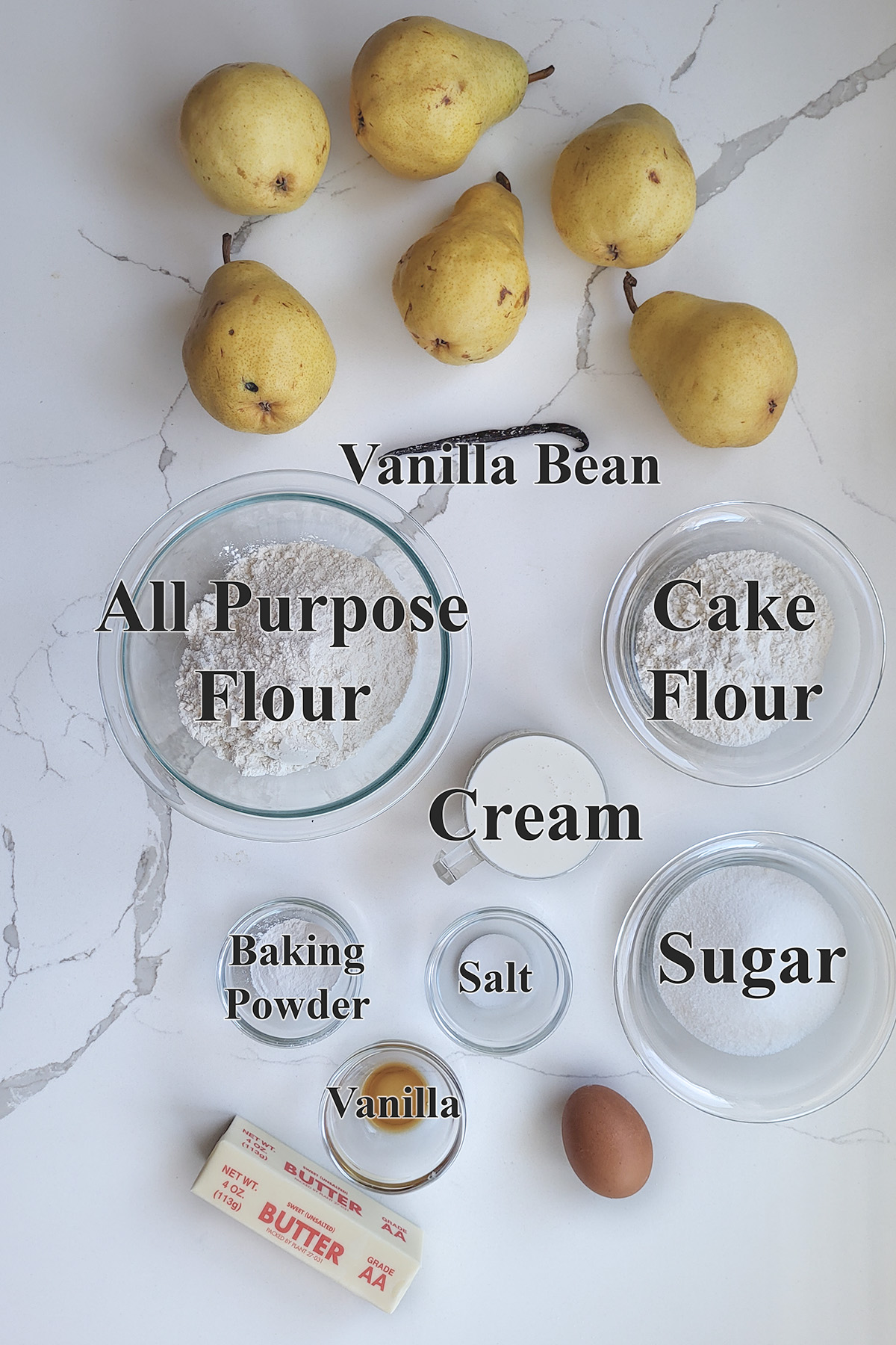 ingredients for pear cobbler in glass  bowls on a white surface.