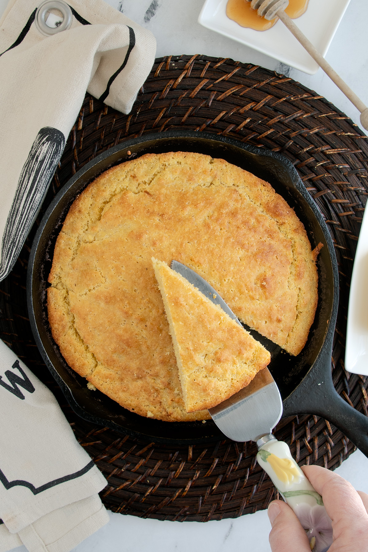 cornbread in a skillet with a slice removed set on a table.