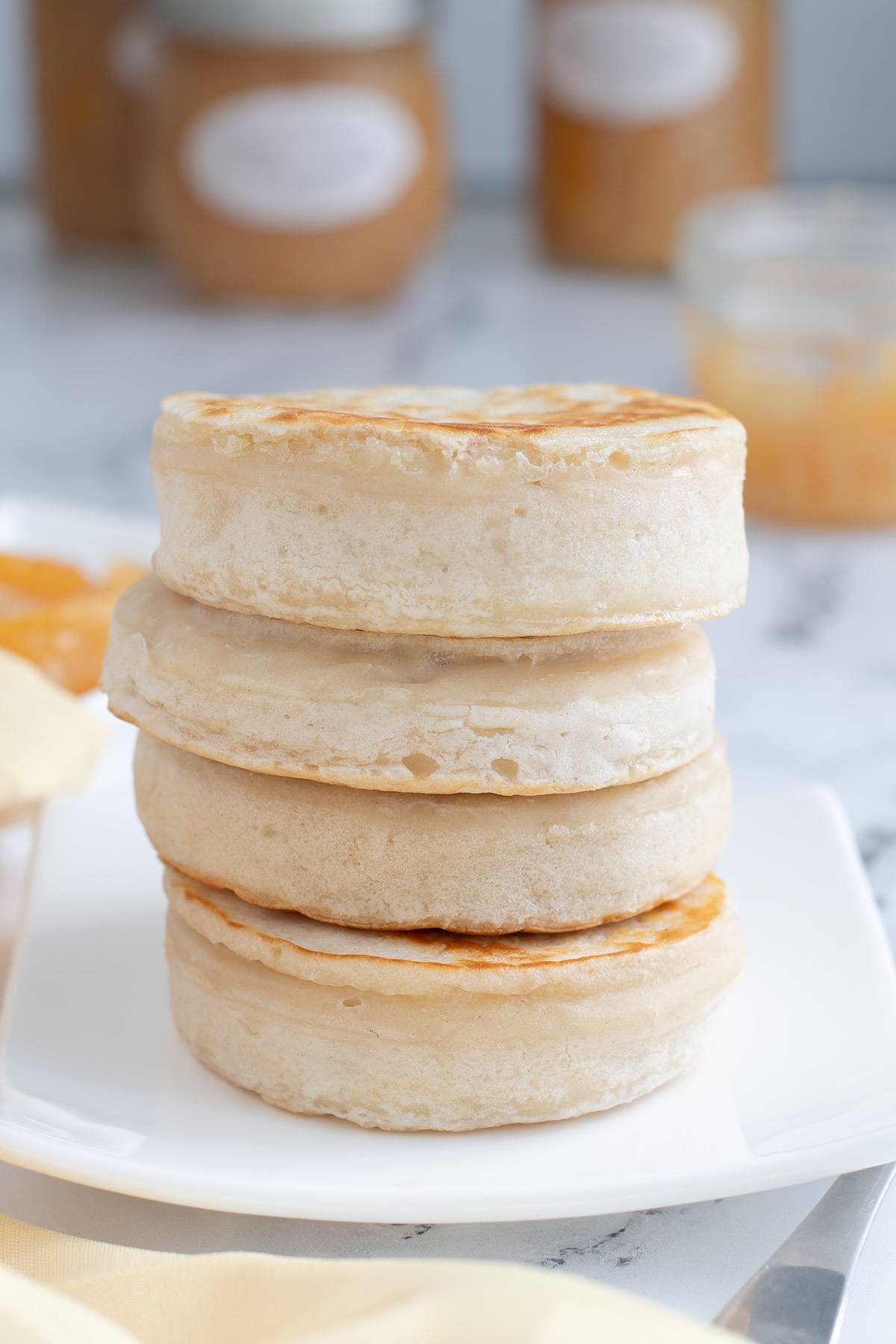 a stack of sourdough crumpets on a white plate.