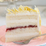 a slice of white chocolate layer cake on a pink plate.