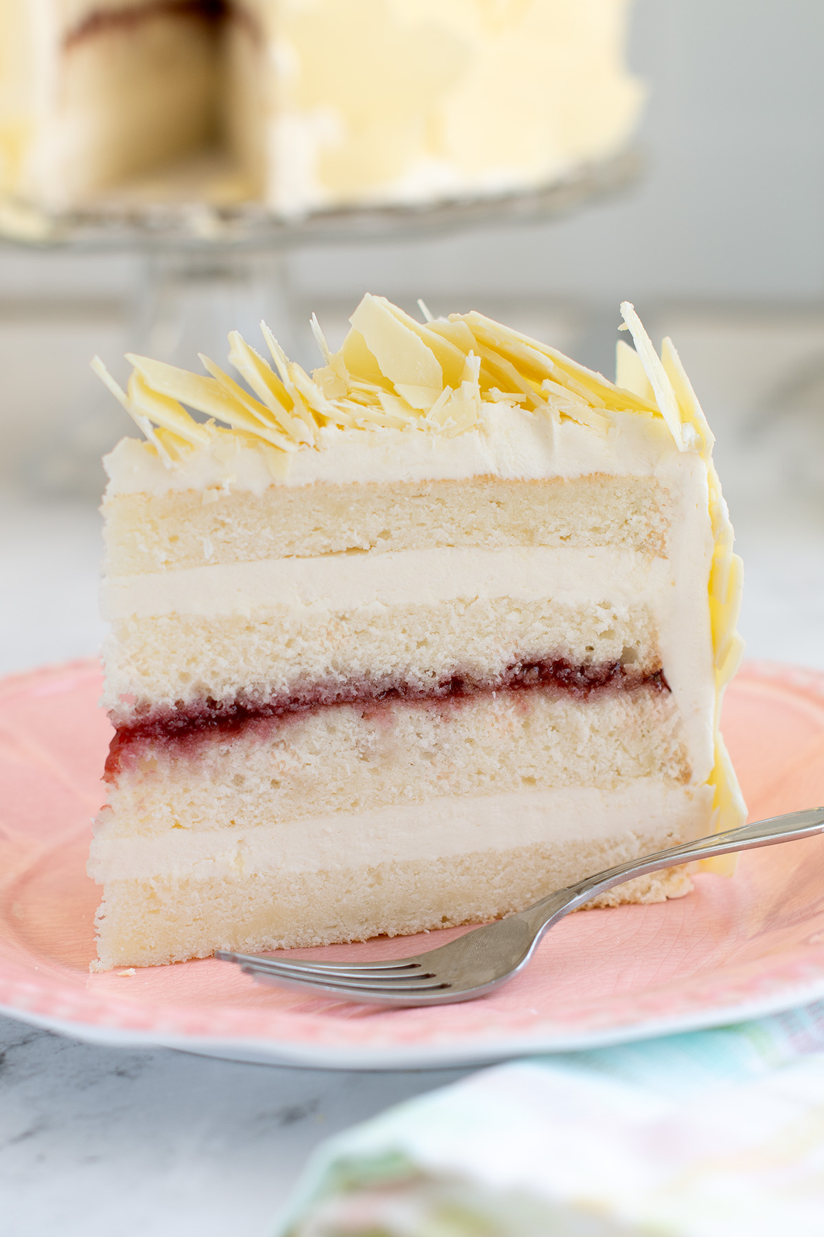 a slice of white chocolate cake on a pink plate.