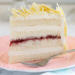 a slice of white chocolate layer cake on a pink plate.