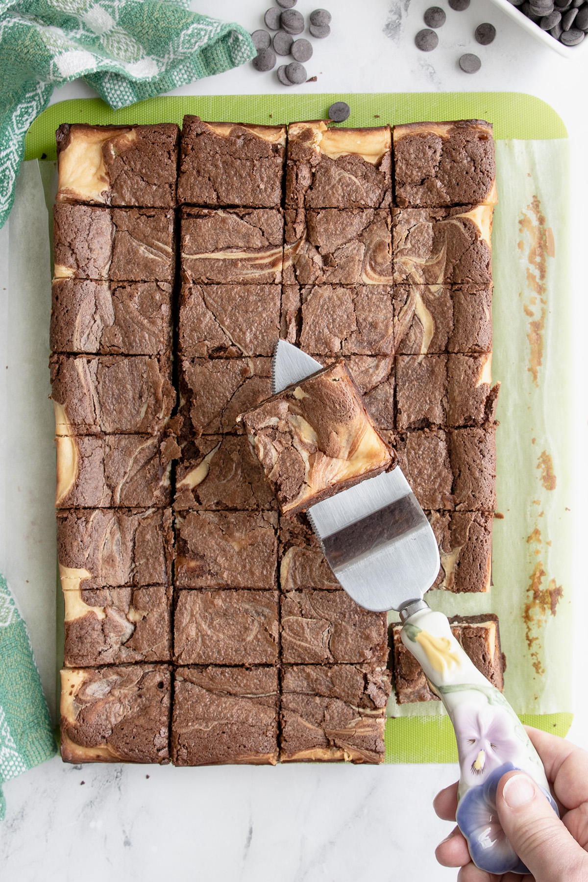 a tray of baileys brownies on a green board with a spatula holding a brownie.